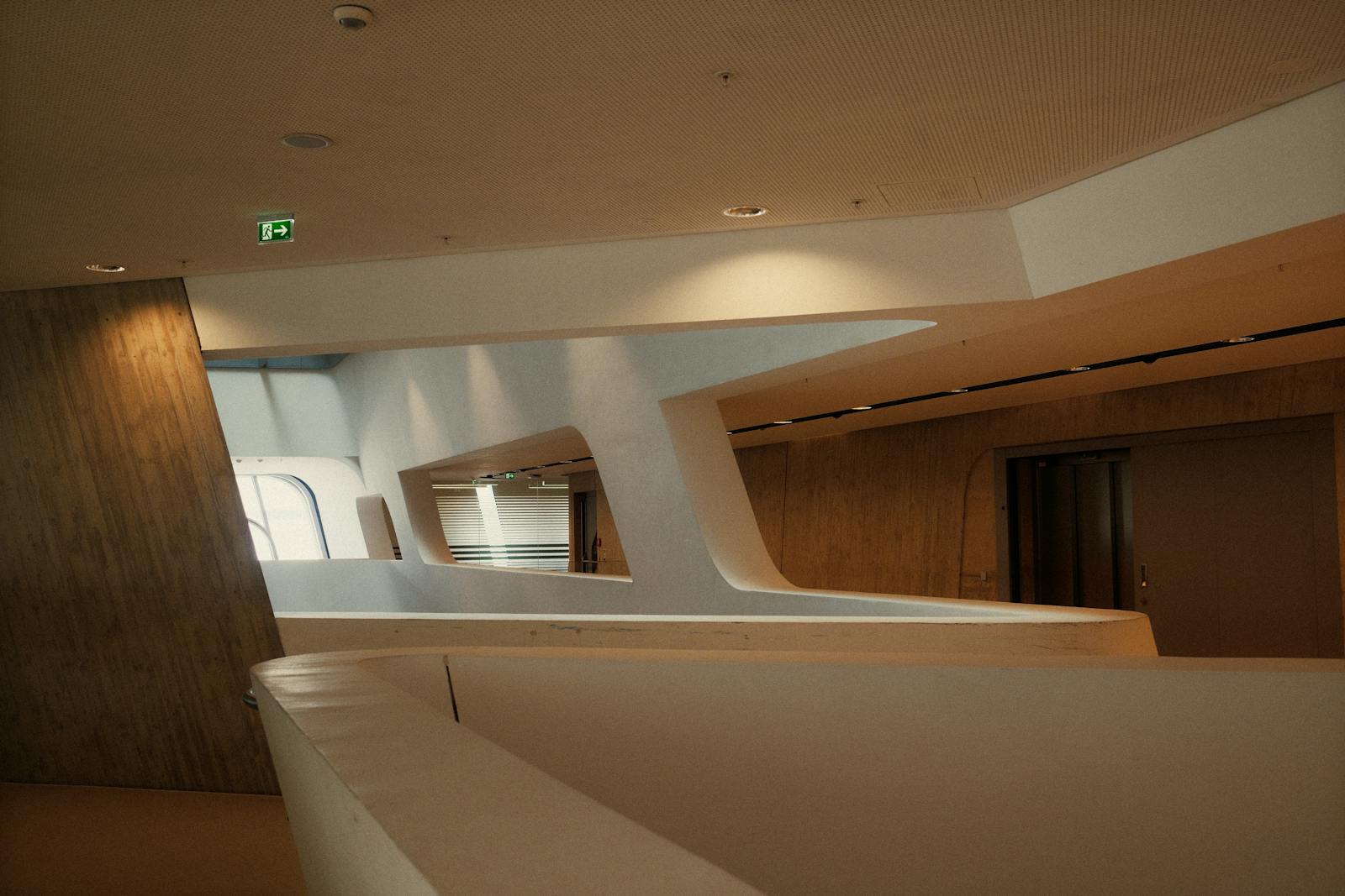 A wide architectural interior — concrete columns and a tall window casting a long shadow on a polished concrete floor.